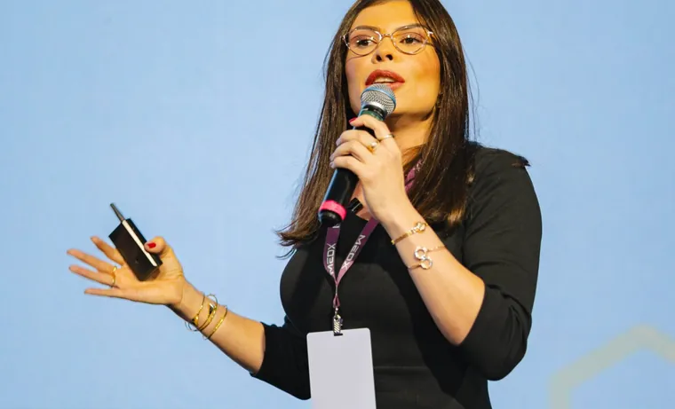 Dra. Emanuelle Jamille ao microfone no palco de um evento médico